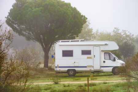 Camping on nature. Camper vehicle at campsite on foggy day. Travel in wintertime.の写真素材