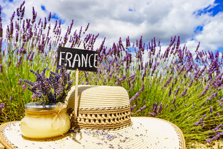 Summer hat, jar with honey and board with sign France against fresh lavender field background. Attraction trip for french vacation in Provence.の写真素材