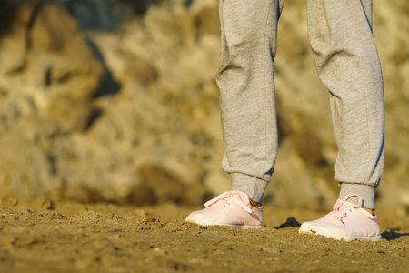 Woman walking on the beach, relaxing. Detail view legs in sneakers. Summer holidays.