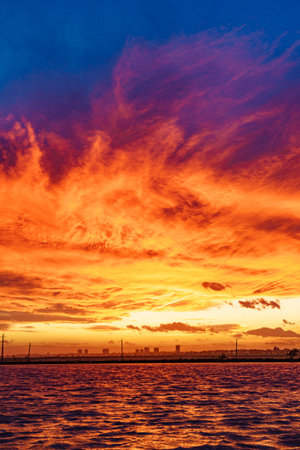 Burning sunset over the sea. Evening coast landscape with city skyline. San Pedro del Pinatar, Murcia Spain.の写真素材