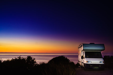 Camper rv at sunrise dawn on mediterranean coast in Spain. Camping on sea shore. Vacation trip in motor home.の写真素材