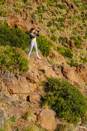 Tourist woman walking with camera, taking travel picture outdoors on mediterranean nature in Spain.の写真素材