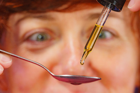 Mature woman preparing spoon with drops medicine, holding dropper. Dietary supplements, cbd oil.の写真素材