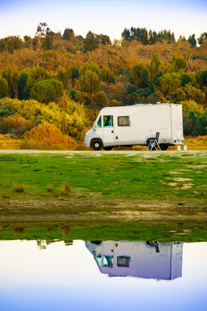 Camping on nature. Camper vehicle at lake shore reflecting in water. Povoa e Meadas Dam in Castelo de Vide, Alentejo Portugal. Travel in motor home.の写真素材