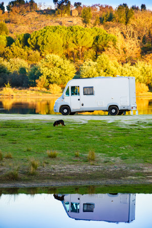 Camping on nature. Camper vehicle at lake shore reflecting in water. Povoa e Meadas Dam in Castelo de Vide, Alentejo Portugal. Travel in motor home.の写真素材