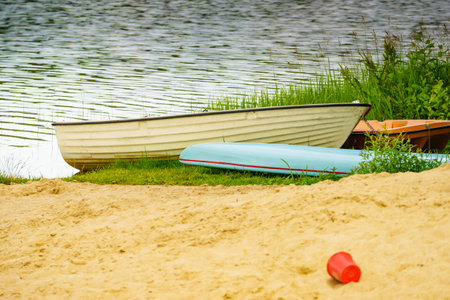 Old wooden fishing boat with paddles on lake shore. Summer activities.の写真素材