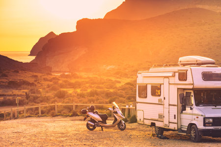 Scooter at camper vehicle camping on mountain nature at sunset. Cabo de Gata Nijar Natural Park, Andalusia Spain. Motor home trip.の写真素材