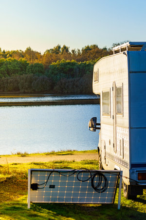 Caravan with portable solar panel camping on autumn nature in Portugal.
