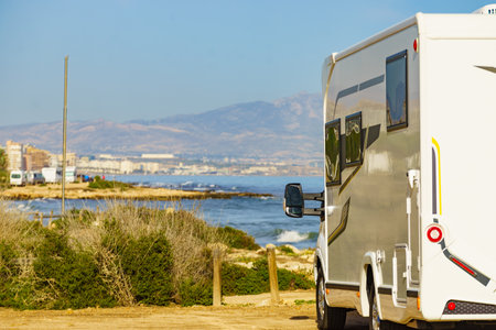 Caravan on mediterranean coast, Alicante city in the distance, Costa Blanca Spain. Wild camping on the beach. Vacation trip with motor home.の写真素材