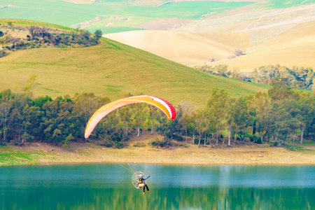 Paragliding. Paraglider flying over spanish nature landscape. Ardales Reservoir, Malaga province in Andalusia, Spain.の写真素材