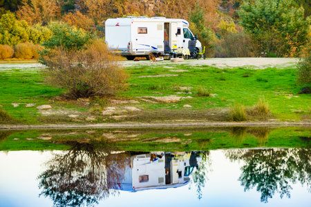 Camping on nature. Camper vehicle at lake shore reflecting in water. Povoa e Meadas Dam in Castelo de Vide, Alentejo Portugal. Travel in motor home.の写真素材