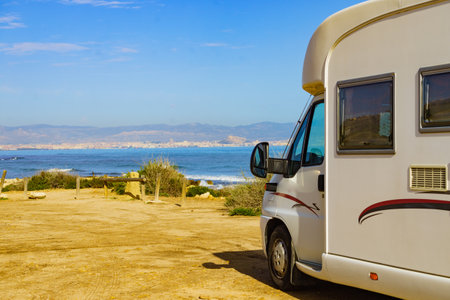 Caravan on mediterranean coast, Alicante city in the distance, Costa Blanca Spain. Wild camping on the beach. Vacation trip with motor home.の写真素材