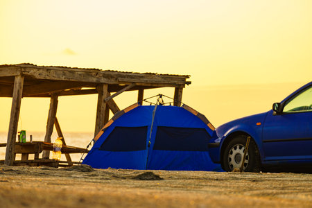 Wooden shelter and tent with car on beach in morning light.の写真素材