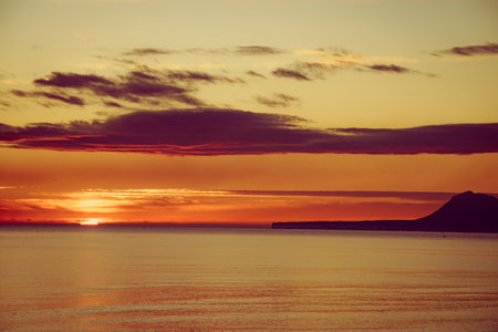 Sunrise over the sea. Montgo mountain massif silhouette on horizon. View from beach near Gandia, Valencia Spainの写真素材