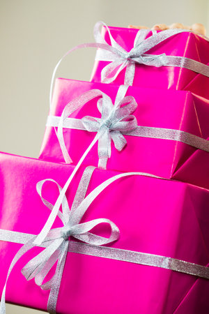 Person holding big stack of presents, pink gift boxes with white ribbons.の写真素材
