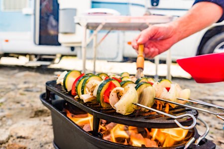 Assorted delicious grilled vegetable skewers on barbecue grill. Barbeque dinner outdoor. Rv camper in the background.の写真素材