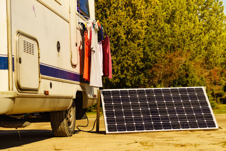 Laundry and portable solar photovoltaic panel, charging battery at camper car rv. Camping on nature.の写真素材