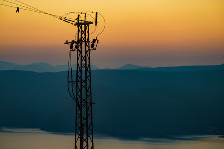 Coast with electricity transmission pylons, power lines high voltage towers. Sunset landscape in Spainの写真素材