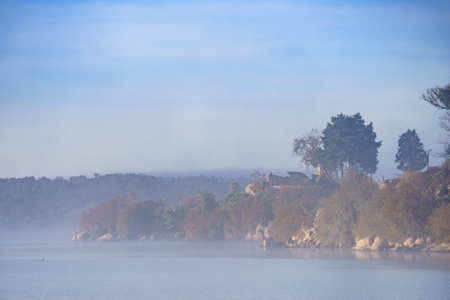 Foggy morning landscape. Fog over autumn lake water. Povoa e Meadas Dam in Castelo de Vide, Alentejo Portugal.の写真素材