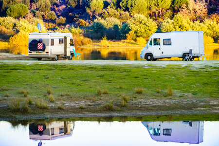 Camping on nature. Camper vehicles at lake shore reflecting in water. Povoa e Meadas Dam in Castelo de Vide, Alentejo Portugal. Travel in motor home.の写真素材