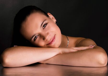 Smiling young woman on silver, black backgroundの写真素材