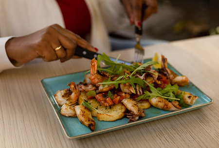 beautiful African-American girl eating seafood salad in a cafeの写真素材