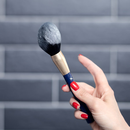 makeup artist shakes off the powder with makeup brush dust hanging in the airの写真素材