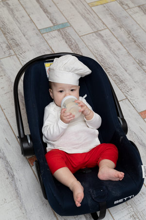 An Asian kid in a chef's hat and apron cooked Christmas ginger cookies with his mom and is now...