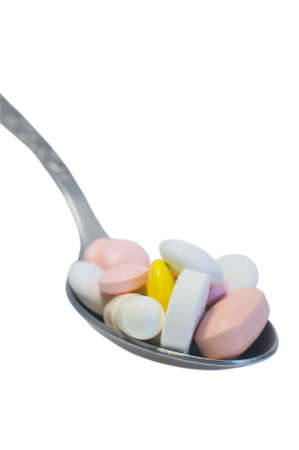 Medical concept  spoon piled with colorful pills  isolated on white の写真素材