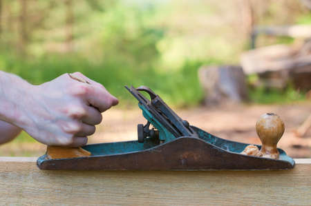 Hands of a carpenter planed wood. Work on the nature.の写真素材