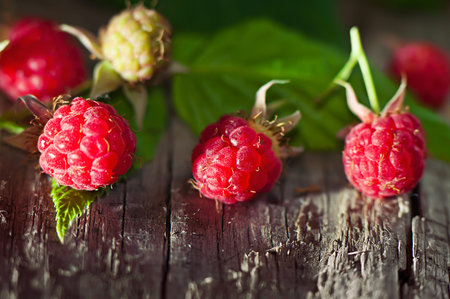 Berries of a ripe raspberry on an old wooden board, the sunlit.