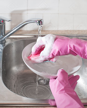 Hands wash the dishes in the kitchen sink with soapy spongeの写真素材