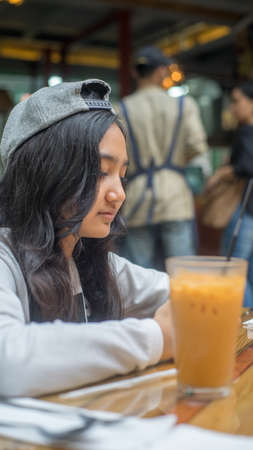 A girl waiting for her food to come in a cafeの写真素材