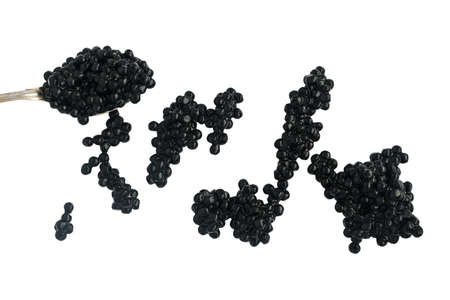 Black caviare in spoon and scattered on the surface isolated on white background. Top viewの写真素材
