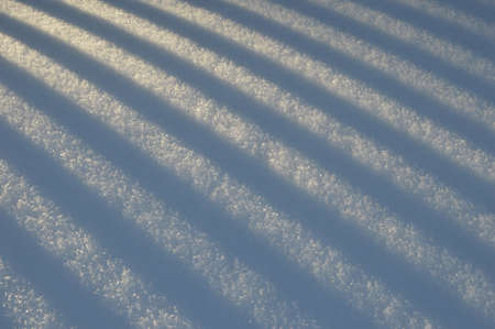 Snow light background with shadow stripes from the fenceの写真素材