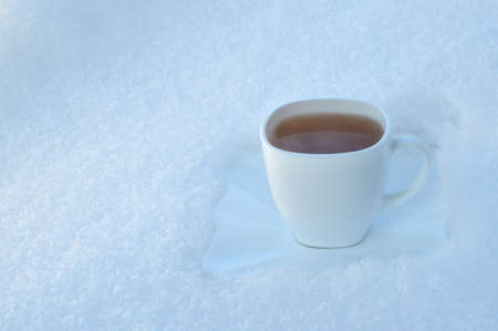 Hot drink in the white cup on snow background outdoorsの写真素材