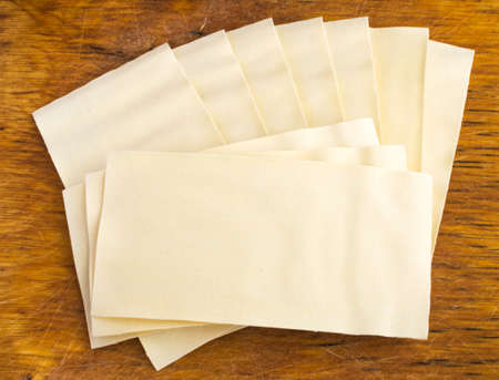 Heap of Uncooked Lasagna Sheets or Dry Italian Pasta on Old Wooden Cutting Boardの写真素材