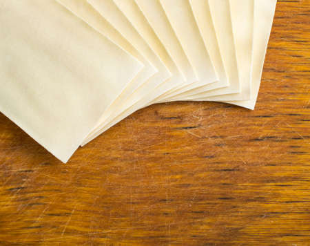 Heap of Uncooked Lasagna Sheets or Dry Italian Pasta on Old Wooden Cutting Boardの写真素材