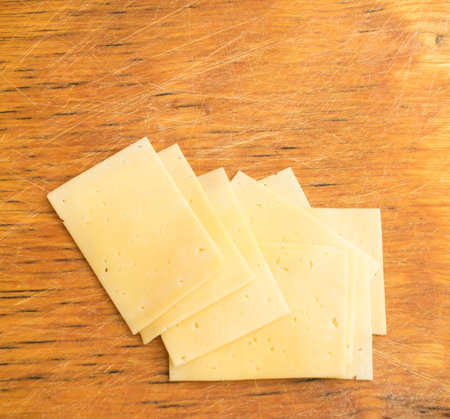 Sliced Cheese Over Rustic Wooden Background with Copy Space