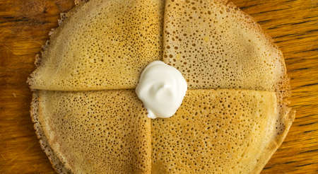 Thin Pancakes with Sour Cream on a Wooden Background Top View. Fresh Homemade Crepesの写真素材