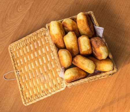 Traditional Homemade Baked Patties or Pies with Jam in a Wicker Basket. Fried Russian Pirozhki made from Yeast Dough in Rustic Styleの写真素材