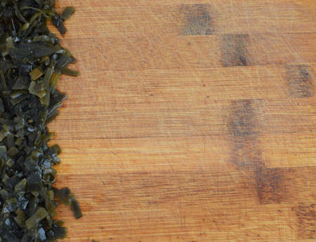 Heap of Dark Green Seaweed Salad on Old Wooden Cutting Board . Pickled Kelp or Laminaria Japonicaの写真素材