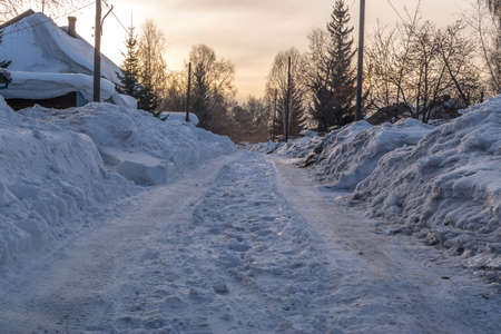 The Street is Covered with Snow in the Evening Light. Russian Village in Early Springの写真素材