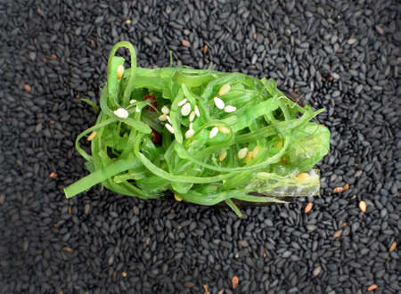 Gunkan Sushi with Green Seaweed Chukka on a Background of Black Sesameの写真素材