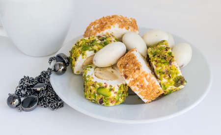 Traditional Turkish Delight Lokum on White Plate Sweet Rolls of Rahat Lokum with Nut Paste, Hazelnut, Pistachio and Sesame. Ramadan Sweetsの写真素材