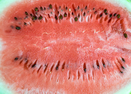 Red watermelon pulp texture with with black seeds. Summer fruit background