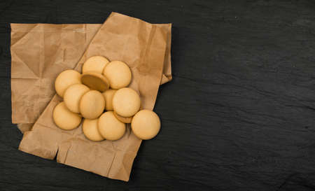 Round Homemade Biscuits Top View on Dark Background. Spilled Cookies with Wrapping Paperの写真素材