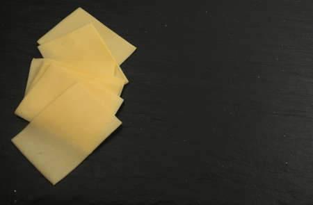Sliced Cheese Over Black Stone Background with Space for Text Top Viewの写真素材