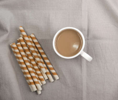 Chocolate Wafer Sticks and Cup of Coffee with Milk on Gray Backgroundの写真素材