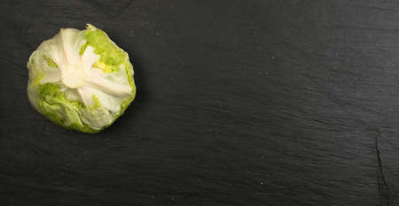 Round Iceberg Lettuce on Black Stone Background. Green Salad Head with Place for Textの写真素材